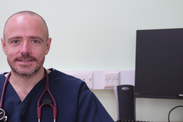 Dr James Crosbie wearing scrubs with stethoscope around his neck